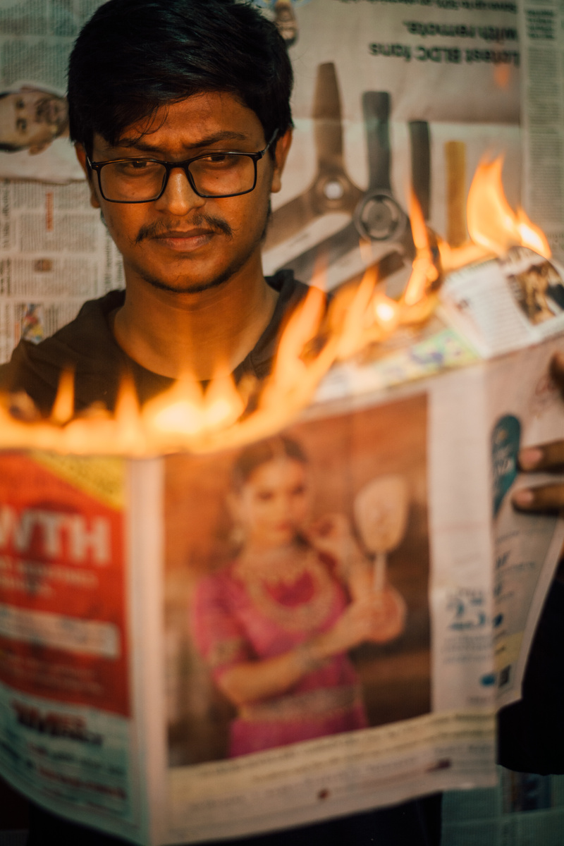 a person holding a newspaper with fire on it