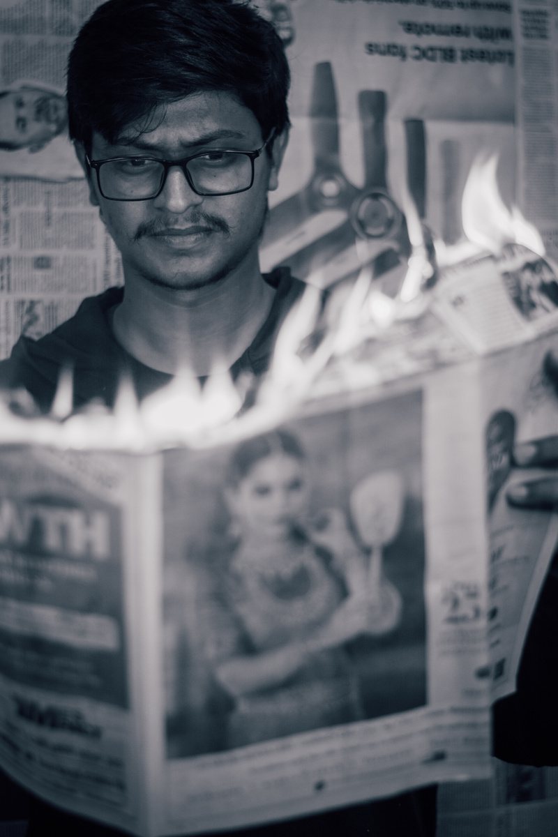 a person holding a newspaper with flames coming out of it