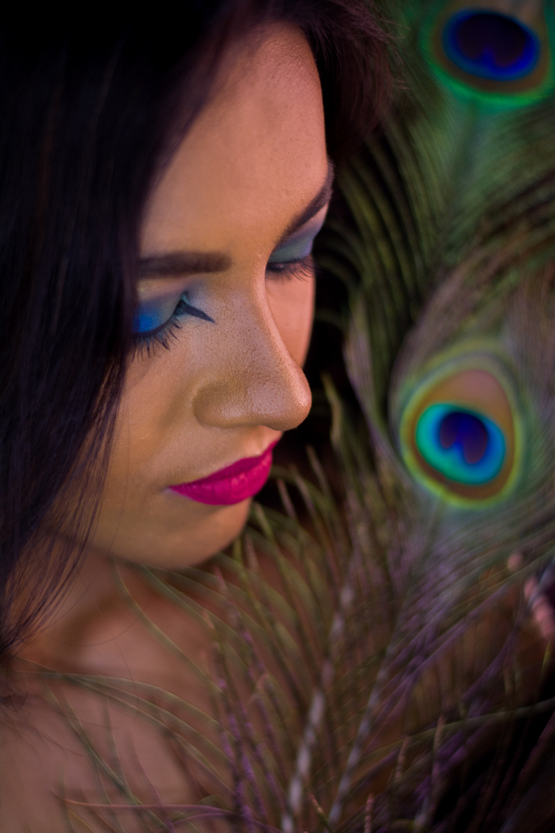 a person with bright makeup and a peacock feather